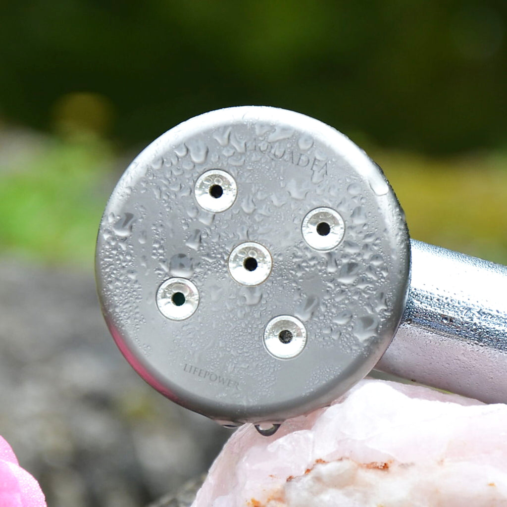 Kleine Rose 5 titanium shower head resting on rose quartz — spray plate with water drops